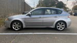 2009 Subaru Impreza Outback Sport AWD, silver color, parked with gray background, features 17" wheels and 92,000 miles.