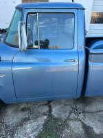 Side view of a 1965 International Harvester D100 pickup truck in blue, showing the door and window details.