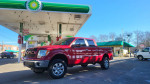 2011 Ford F-150 Lariat 4WD parked at gas station, showcasing its red exterior and chrome wheels.