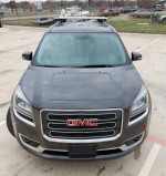 Front view of a 2013 GMC Acadia SLT with roof racks, clean condition, parked in an open lot.