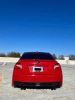 2016 Subaru WRX Limited AWD in red, parked in an open area, showcasing its rear view and aftermarket modifications.
