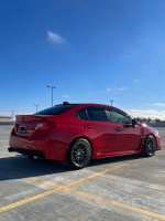 2016 Subaru WRX Limited AWD in red, parked with a clear blue sky, showcasing modified aftermarket wheels.