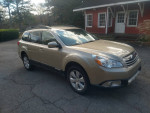 2010 Subaru Legacy in excellent condition, gold color, parked outside a rustic building.