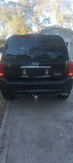 Rear view of a black 2008 Infiniti QX56 on a driveway, showcasing its sleek design and tow hitch.
