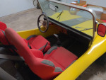 Interior view of a yellow 1970 Volkswagen Dune Buggy with red racing seats and custom dashboard.