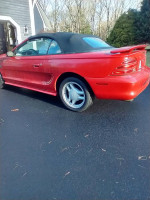 1994 Ford Mustang GT Convertible in red, showcasing low mileage and a black soft top.