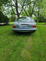 Rear view of a 2003 Jaguar XJ8 in zircon blue parked on green grass.