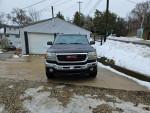 Front view of a 2005 GMC 2500 SLT Duramax in gray, parked on a snowy driveway.