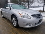 2012 Nissan Altima 2.5S sedan in silver color, parked on wet road with trees in background