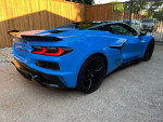 2023 Chevrolet Corvette Z06 in Rapid Blue with black accents, parked outdoors, showcasing sleek design and features.