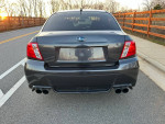Rear view of a 2014 Subaru Impreza WRX Sedan parked on the road with sunset in the background.