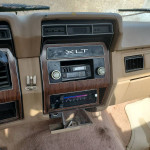 Interior view of a classic 1984 Ford F250 XLT dashboard with vintage radio and worn features.