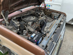Engine compartment of a 1987 Ford F250 pickup truck with new battery and alternator visible.