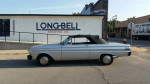 1964 Ford Falcon Convertible with silver body and black power top parked near a brewery