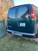 Green 2010 Chevrolet Express cargo van parked, showcasing its rear and license plate.