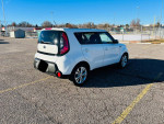 White 2015 Kia Soul parked in a lot, showcasing its clean exterior and modern design.