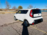 2015 Kia Soul parked with a clear blue sky, showcasing its white exterior and modern design.