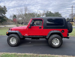 Red 2005 Jeep LJ Unlimited 2 Door parked on pavement, showcasing its off-road capabilities and modified features.