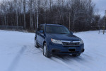 2010 Subaru Forester 2.5X AWD parked in snow, showcasing its robust design and all-season tires for optimal performance.