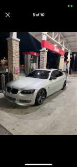 BMW 335i with upgrades parked at a gas station, showcasing its sleek design and new tires.