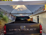 Rear view of a 2003 Chevrolet Silverado parked under a canopy, showcasing its truck bed design.