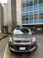 Front view of a 2013 Ford Escape SEL in Sterling Gray Metallic parked near a modern building