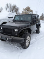 2014 Jeep Wrangler Sahara in snow, showcasing 4WD features and good tire condition with 106,000 miles.