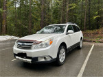 2011 Subaru Outback 2.5i AWD parked in a forest, showcasing its immaculate exterior and all-wheel drive features.