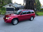 Red Subaru XT with AWD parked on a residential street, showcasing its exterior design and snow-ready features.