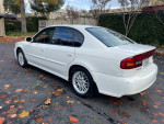 2004 Subaru Legacy sedan in white color parked on a driveway with autumn leaves.