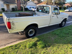 Side view of a used 1991 Ford F250 Super Duty truck parked on the street, showcasing its long bed and typical wear.