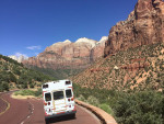 1997 Ford E-350 traveling on a scenic road with mountains and clear blue skies