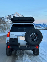 Rear view of a 2010 Lexus GX 460 4WD parked in snowy mountains, showcasing overland modifications.