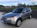 2011 Subaru Forester limited edition in silver, parked on a sidewalk with clear skies.