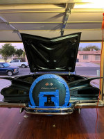Rear view of a 1959 Chevrolet Impala showcasing its chrome details and spare tire cover in a garage.