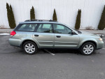 2009 Subaru Outback with 5-speed manual transmission parked in a driveway, showcasing its all-wheel-drive features.