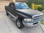 1999 Dodge Ram 1500 4x4 X-Cab with 188k miles parked in driveway, featuring a matte black exterior and chrome details.