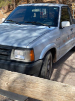 Mazda B2600 truck with regular cab parked near a wooden fence, showcasing its condition and design.