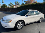 2004 Ford Taurus SES in white, showing clean exterior, parked on a sunny street with palm trees in the background.