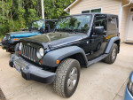 2010 Jeep Wrangler Mountain Edition in black with manual transmission, parked in a residential area.