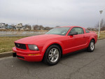 2007 Ford Mustang in red parked by the waterfront, featuring an overdrive and fuel-efficient settings.