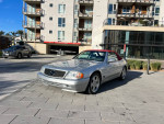 2000 Mercedes-Benz SL500 convertible with burgundy soft top and low mileage parked in front of modern apartments.