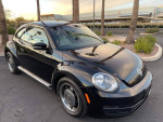 Black 2016 Volkswagen Beetle Coupe parked with palm trees, showcasing sleek design and modern features.