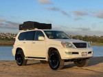 2008 Lexus GX 470 4WD in pearl white, ready for off-road adventures near water, with camping gear on roof.