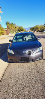 2009 Toyota Camry LE in gray color parked on a sunny street with palm trees, well-maintained and clean.