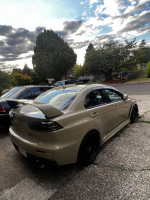 2011 Mitsubishi Lancer EVO X GSR with upgrades parked outside under cloudy sky.