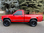 1997 GMC Sierra 1500 SL 4WD in red, side view showcasing its short bed and off-road tires.