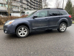 2013 Subaru Outback wagon in gray, featuring AWD, heated leather seats, parked on a rainy street.