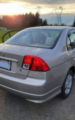 2004 Honda Civic EX in silver with low mileage and aftermarket headlights, parked outdoors at sunset.