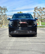 Front view of a 2022 GMC Sierra X31 SLT, black exterior, parked outdoors with scenic background.